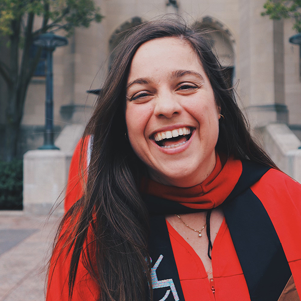 Photo of Michelle Eastman (STH’22). Eastman is caught candidly laughing as she wears a red graduation gown.